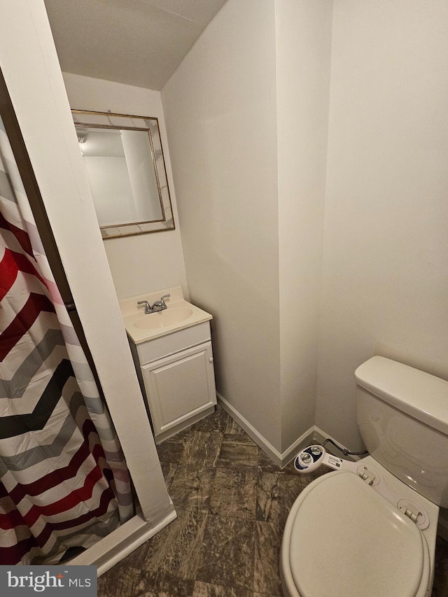 full bathroom with a stall shower, vanity, toilet, and baseboards