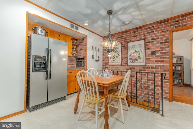 dining room with light tile patterned floors, visible vents, brick wall, and an inviting chandelier