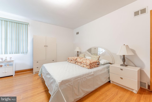 bedroom featuring baseboards, visible vents, and light wood finished floors