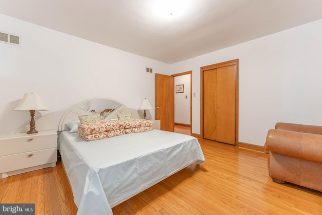 bedroom with light wood-style floors, a closet, and visible vents