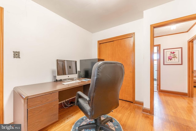 office space featuring crown molding, light wood-style flooring, and baseboards