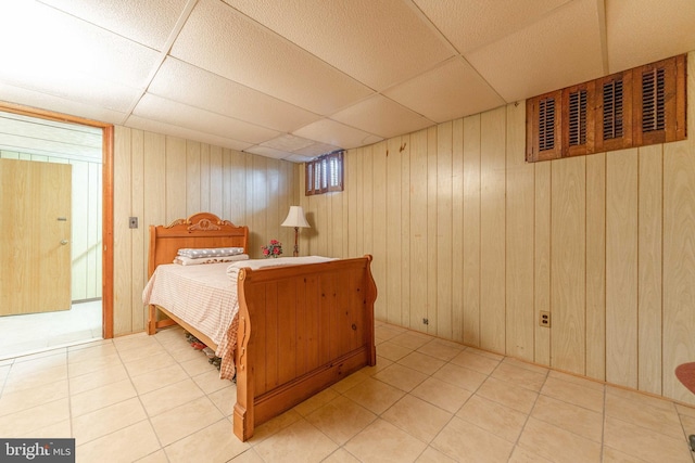 tiled bedroom with a paneled ceiling and wood walls