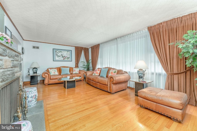 living area featuring ornamental molding, a fireplace, wood finished floors, and visible vents