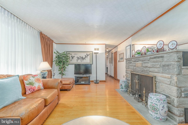 living area featuring crown molding, visible vents, a fireplace, and wood finished floors