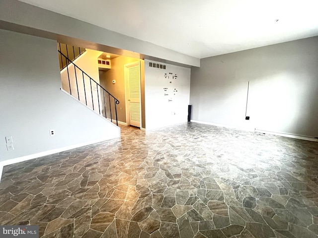 unfurnished living room featuring stairs, baseboards, visible vents, and stone floors