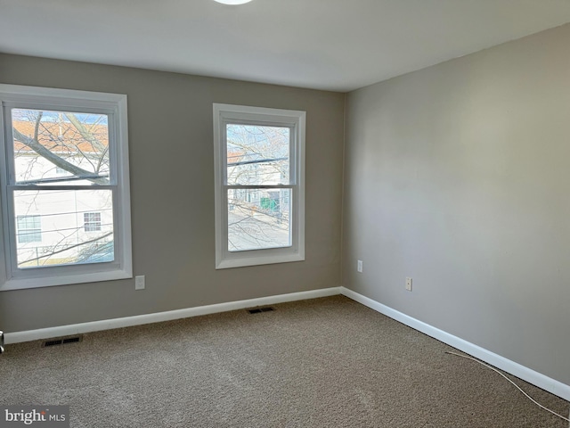 spare room with carpet floors, visible vents, and baseboards