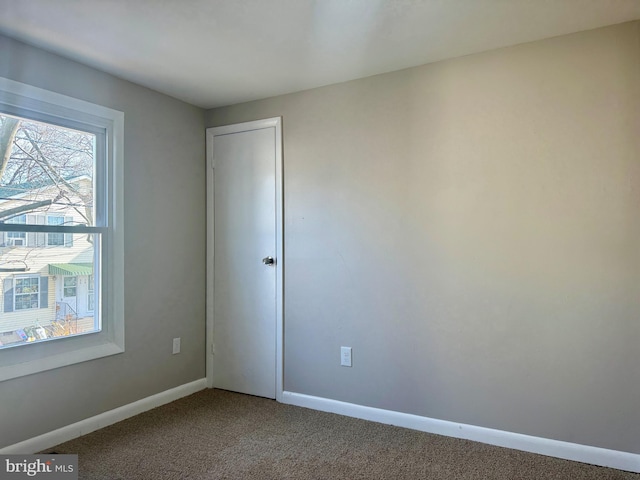 carpeted empty room featuring baseboards