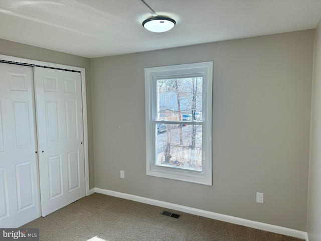 unfurnished bedroom featuring carpet floors, baseboards, visible vents, and a closet