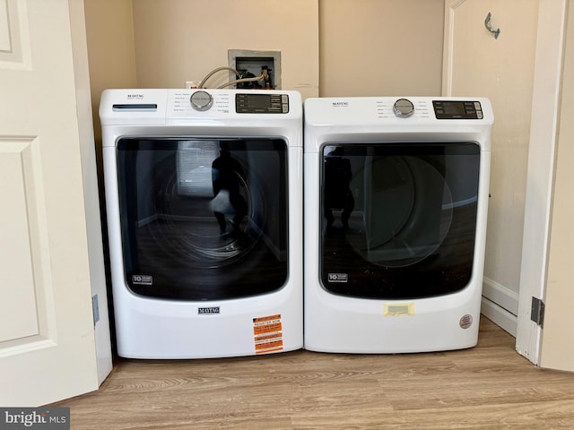 clothes washing area featuring laundry area, light wood-style flooring, and washer and dryer