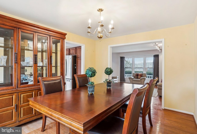 dining room featuring light wood finished floors, baseboards, and an inviting chandelier