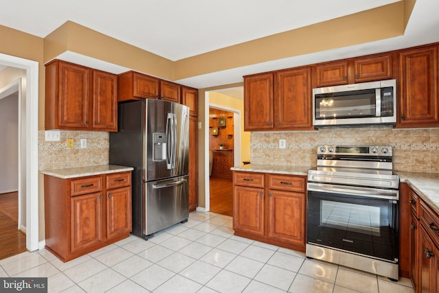 kitchen with brown cabinets, tasteful backsplash, and stainless steel appliances