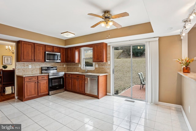 kitchen featuring brown cabinets, visible vents, backsplash, appliances with stainless steel finishes, and a sink