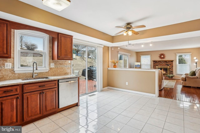 kitchen with decorative backsplash, dishwasher, a sink, and light tile patterned floors