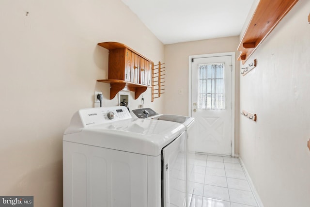 clothes washing area with light tile patterned floors, laundry area, baseboards, and washer and dryer