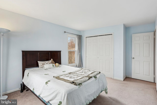 bedroom with a closet, light colored carpet, and baseboards