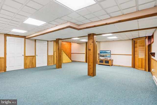 finished below grade area featuring a wainscoted wall, carpet floors, wood walls, and a paneled ceiling