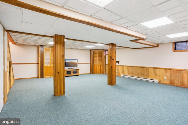 finished below grade area featuring a baseboard heating unit, a paneled ceiling, wainscoting, and carpet floors