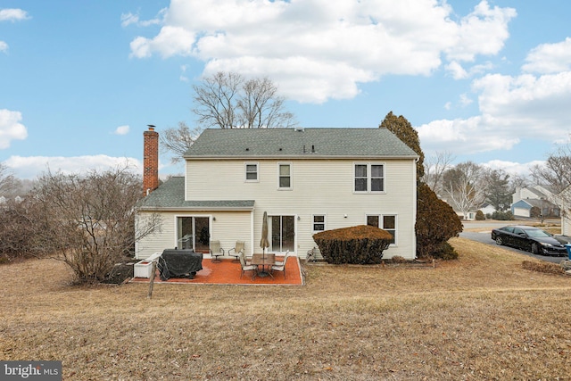 back of house with a yard, a chimney, and a patio area