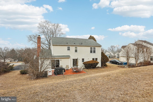 back of property with a patio, a chimney, and a lawn