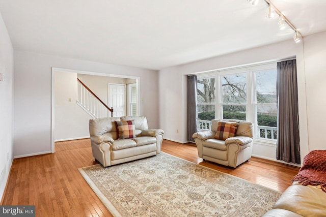 living room with stairway, light wood-style flooring, and track lighting