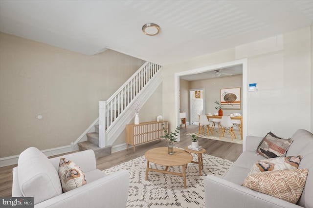 living room featuring stairs, wood finished floors, and baseboards