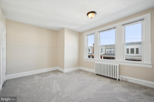 carpeted spare room with radiator heating unit and wainscoting