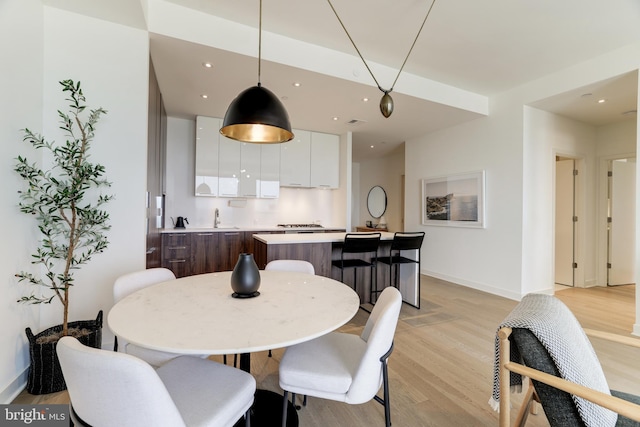 dining area featuring light wood finished floors, baseboards, and recessed lighting