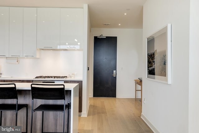 kitchen with light countertops, white gas cooktop, light wood-style floors, white cabinetry, and modern cabinets