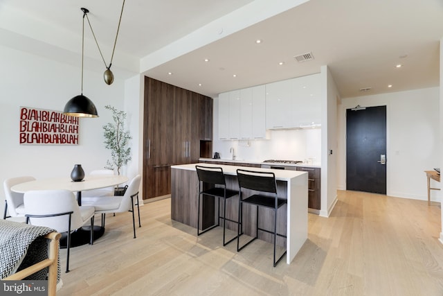 kitchen featuring white cabinets, light countertops, hanging light fixtures, a center island, and modern cabinets