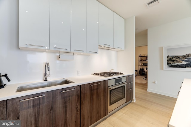 kitchen with visible vents, white cabinets, appliances with stainless steel finishes, light countertops, and a sink