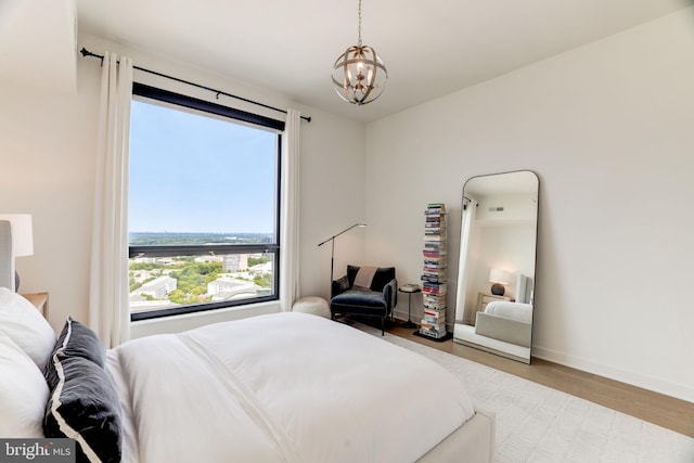 bedroom featuring light wood-style floors, a notable chandelier, and baseboards