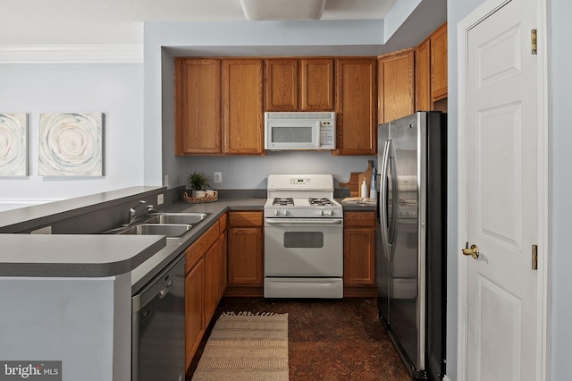 kitchen featuring brown cabinetry, white appliances, and a sink