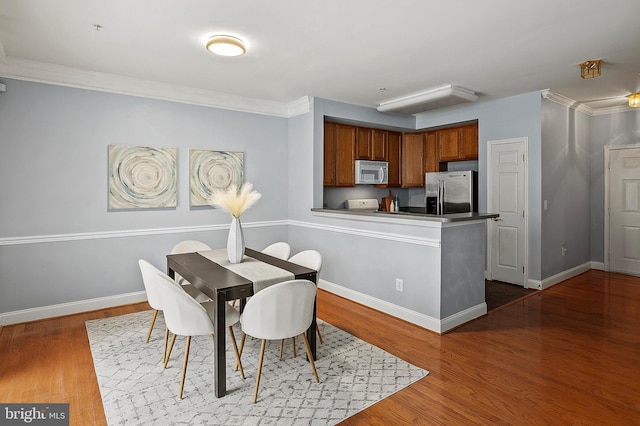 dining area featuring baseboards, wood finished floors, and ornamental molding