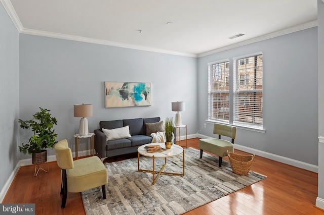 living area featuring baseboards, crown molding, visible vents, and wood finished floors