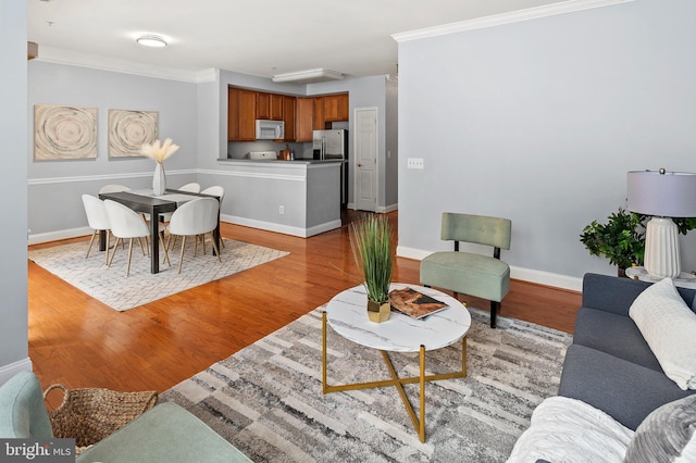 living room featuring baseboards, light wood-type flooring, and crown molding