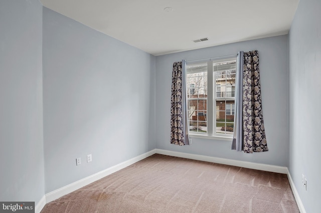 empty room with carpet flooring, visible vents, and baseboards