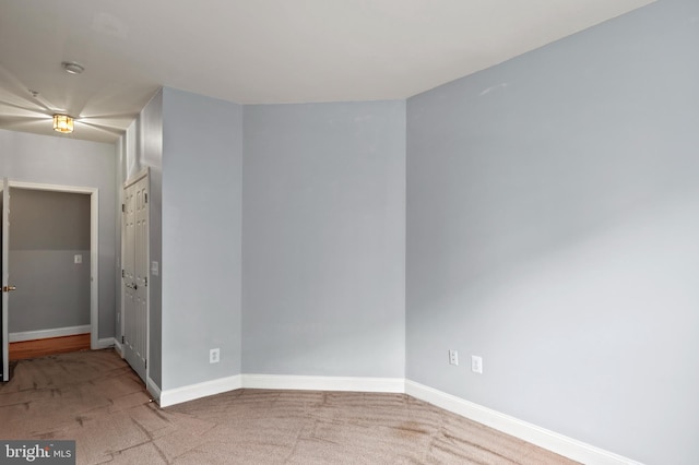 spare room featuring baseboards and light colored carpet