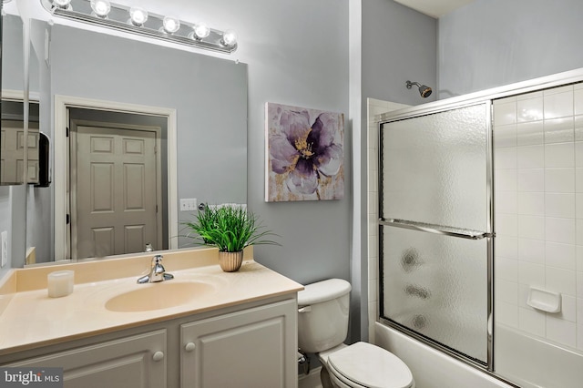 bathroom with toilet, shower / bath combination with glass door, and vanity