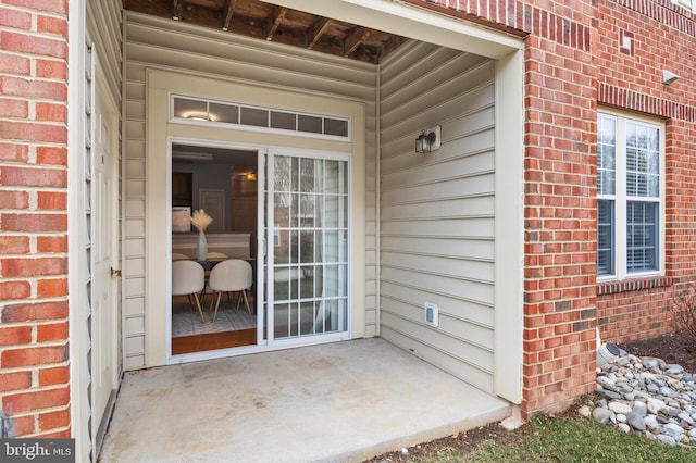 property entrance with brick siding and a patio area