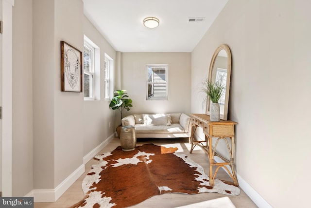 living area featuring baseboards, visible vents, and wood finished floors