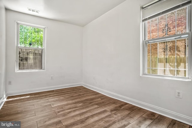 unfurnished room with visible vents, baseboards, and wood finished floors