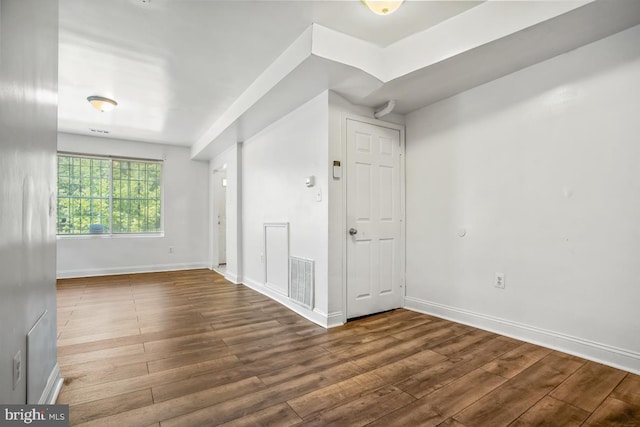 unfurnished room with baseboards, visible vents, and wood finished floors