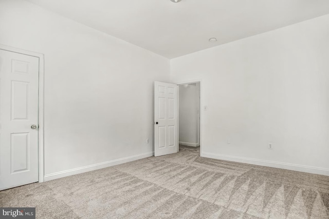 spare room with baseboards and light colored carpet