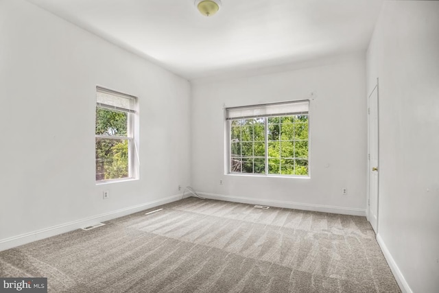 carpeted spare room with visible vents and baseboards