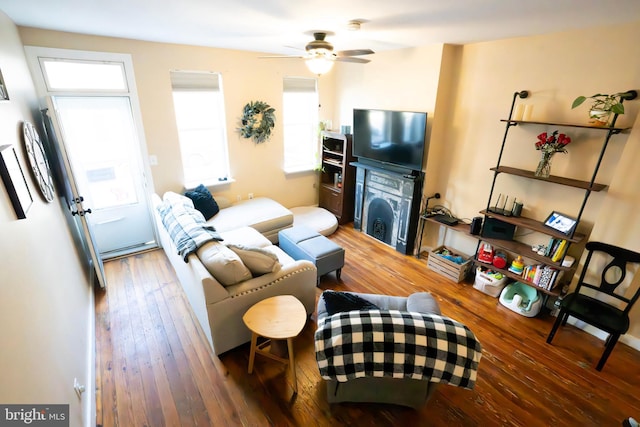 living area with ceiling fan, a fireplace, and wood finished floors