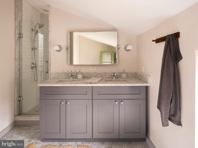 full bathroom featuring double vanity, a stall shower, lofted ceiling, and a sink