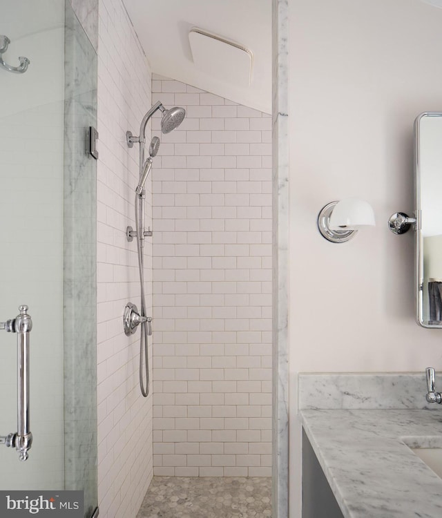 full bath with a stall shower, vanity, and lofted ceiling