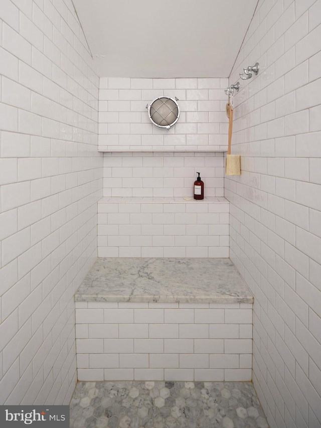 bathroom featuring a tile shower and vaulted ceiling