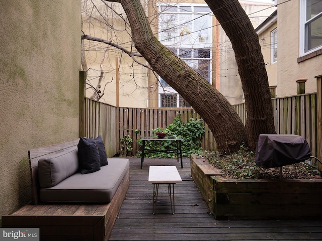 deck with an outdoor hangout area, a grill, and fence