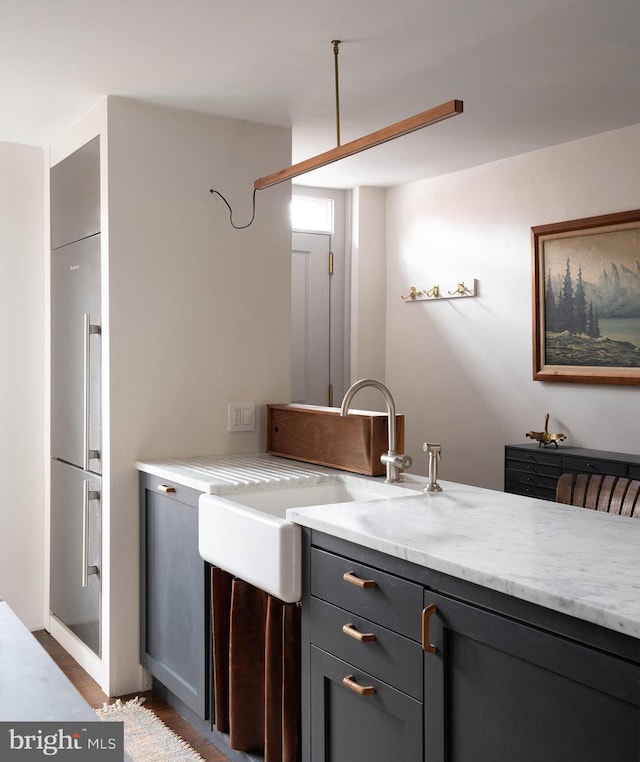 kitchen featuring a sink, light stone counters, and gray cabinetry